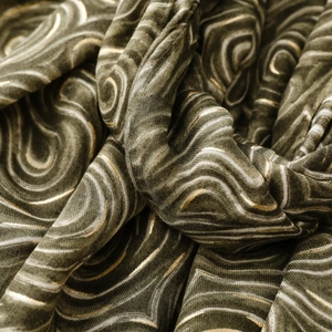 Détail du tissu vert olive avec imprimé latte doré et textures métalliques scintillantes