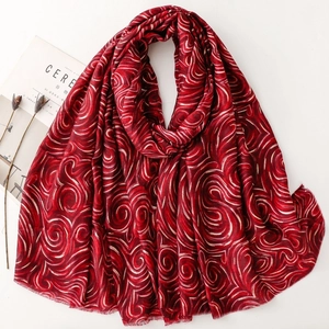 Détail du foulard en coton et lin rouge foncé avec motifs tourbillons dorés et bords bruts