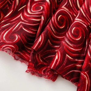 Gros plan d'un tissu satiné rouge foncé avec des spirales dorées et une texture soyeuse