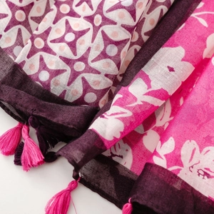 Detail of bohemian floral cotton-linen scarf with colorful geometric patterns and pink tassels