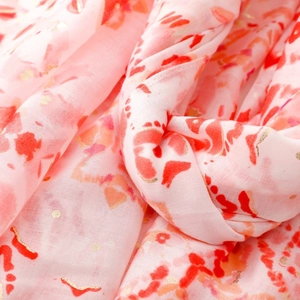 Dettaglio di sciarpa rosa chiaro con stampe acquerello rosse e pois dorati