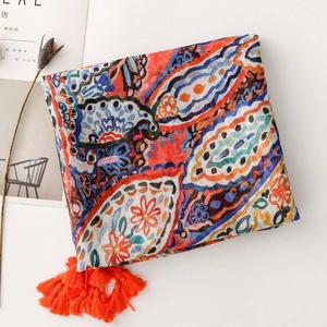 Close-up of bohemian paisley scarf featuring colorful floral patterns and orange tassels