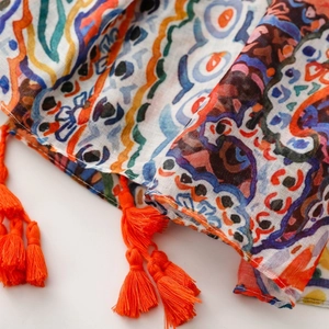 Close-up of bohemian paisley printed scarf featuring colorful patterns and orange tassels