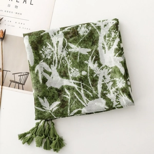 Detail of green and beige printed scarf featuring dragonflies, flowers and fringe tassels