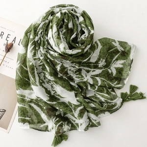 Detailed shot of white scarf with green leaf print and delicate fringe tassels