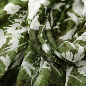Detailed macro view showing the floral pattern and breathable linen texture of the green shawl