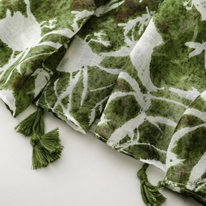 Detail of green leaf pattern on cotton linen scarf with elegant fringe tassels