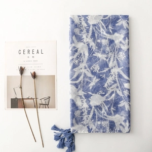 Close-up of vintage blue scarf featuring white botanical silhouettes and fringe tassels