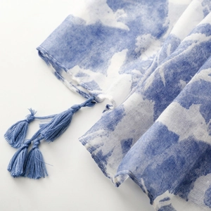 Detail of blue and white watercolor floral scarf with soft tassel edges and woven texture
