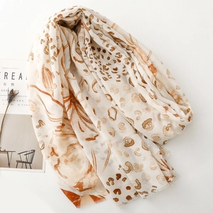 Detail of lightweight leopard floral scarf with raw fringe edges next to a magazine