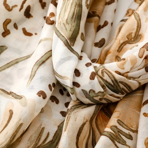 Macro detail of lightweight satin scarf showing leopard and floral patterns in warm tones