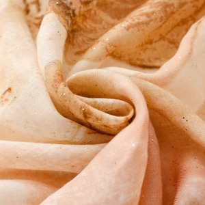 Macro shot of satin scarf fabric with warm marble pattern and delicate gold glitter details