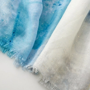 Detailed close-up of blue iris silk scarf with golden glitter and fringed edges