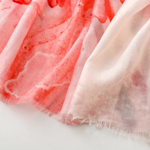 Macro detail of red marble pattern scarf with sparkling gold glitter and frayed edges