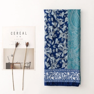 Detail of blue paisley print shawl with floral border next to a magazine and dried flowers