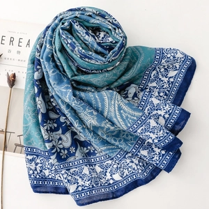 Detail of teal gradient scarf with paisley floral pattern on minimalist white background