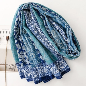 Detailed texture of blue paisley floral shawl next to a magazine and dried flower