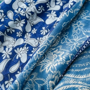 Detailed close-up of blue paisley silk scarf fabric showing intricate floral patterns