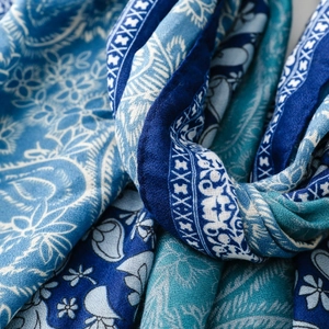 Detailed view of intricate blue paisley floral patterns on soft luxury scarf fabric
