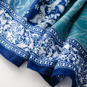 Detailed macro view of bohemian paisley floral pattern on blue silk shawl fabric texture