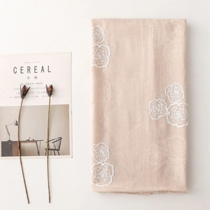 Detail of white rose embroidery on a beige linen ethnic style scarf with floral motifs