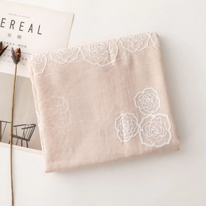 Detailed embroidery of white roses on a light beige scarf with rustic dried floral decor