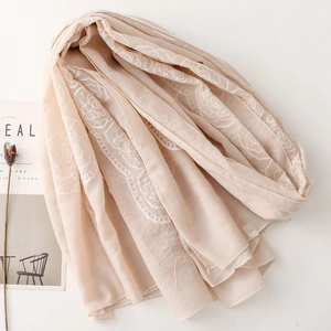 Detail of beige ethnic scarf featuring white floral rose embroidery and wavy lace trim