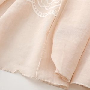 Detail of light apricot ethnic scarf with intricate white lace floral embroidery and hem stitching