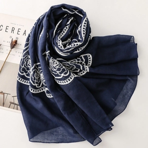 Detail of navy blue ethnic shawl with white floral spiral embroidery on fabric