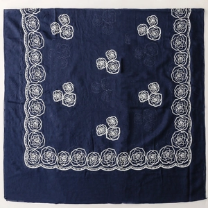 Detailed embroidery of white roses on a navy blue square scarf with textured fabric