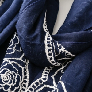 Detailed macro view of white floral rose embroidery on navy blue ethnic style scarf fabric