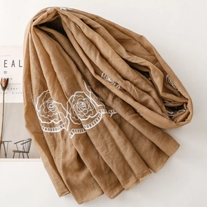 Detailed embroidery of white roses on a lightweight camel cotton-linen scarf
