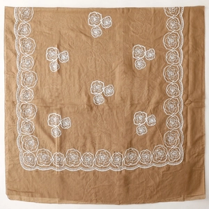 Detailed view of white rose embroidery on a vintage brown linen-style ethnic shawl