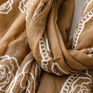 Close-up of intricate white floral embroidery on premium brown cotton linen fabric
