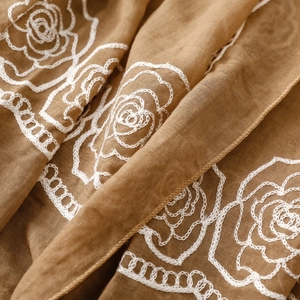 Macro detail of white rose embroidery on khaki ethnic cotton linen shawl fabric