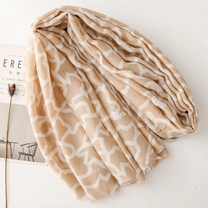 Dettaglio sciarpa beige con motivi geometrici, bordi a frange e trama in cotone lino