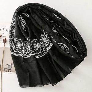 Close-up of white rose embroidery on lightweight black scarf with semi-transparent texture