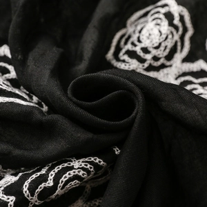 Macro shot of white rose embroidery on high-quality black fabric with detailed texture