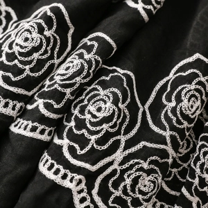 Detailed view of white floral rose embroidery on black ethnic style textured scarf fabric