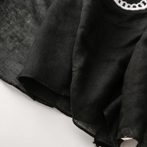 Macro detail of black linen texture scarf featuring white floral chain embroidery