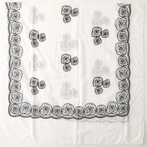 Detail of white scarf featuring black rose floral embroidery and scalloped edges