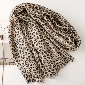 Detailed view of leopard print scarf with frayed edges on a minimalist white backdrop