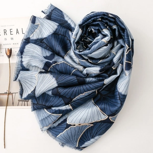 Detail of blue ginkgo leaf scarf with gold foil accents and natural fringed edges