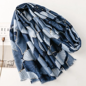 Detail of blue cotton-linen scarf with golden ginkgo leaf print and fringe edges