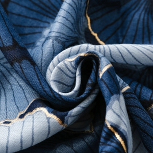 Detail of soft blue satin scarf fabric with elegant gold ginkgo leaf line patterns