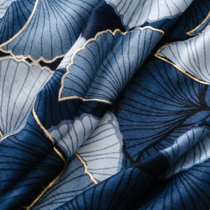 Detail of navy silk scarf featuring blue ginkgo leaves with elegant golden printed edges