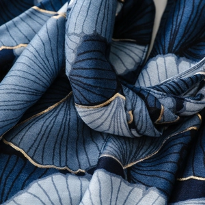 Detail of blue gradient scarf with golden ginkgo leaf pattern and silky texture