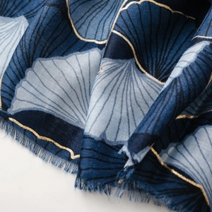 Detailed view of soft navy shawl featuring metallic gold ginkgo leaf patterns and fringe