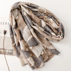 Detail of soft cotton linen scarf with golden ginkgo leaf print and delicate fringe edges