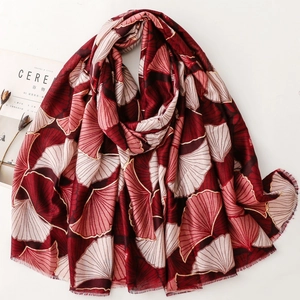 Detail of red scarf with golden ginkgo leaf print and delicate fringe edges